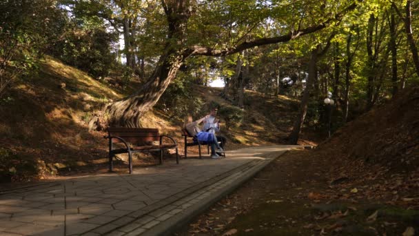 4k, Zeitlupe, das Mädchen und der Mann mit der Kamera sitzen auf einer Bank an einem malerischen Ort. — Stockvideo