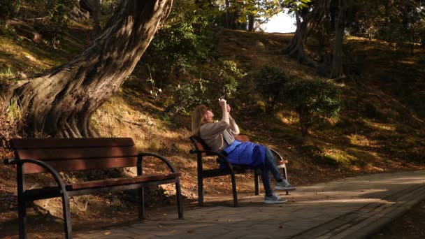 4k, au ralenti, fille avec une caméra assise sur un banc dans un endroit pittoresque . — Video