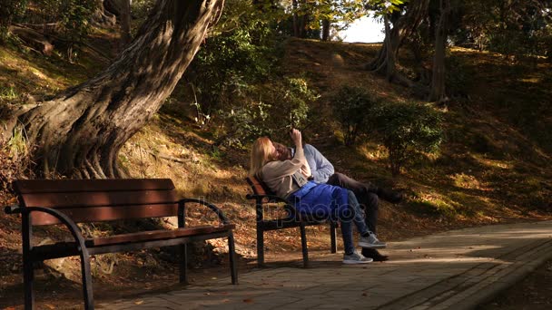 4k, slow motion, the girl and the guy with the camera are sitting on a bench in a picturesque place. — Stock Video