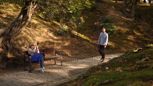 4k, au ralenti, fille avec une caméra est assis sur un banc dans un endroit pittoresque. Les passants passent devant .