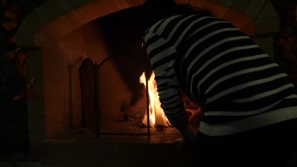 Ogień w kominku. 4k, zwolnionym tempie. Kobieta kładzie drewno w kominku — Wideo stockowe