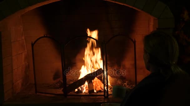 Feu dans une cheminée, 4k, au ralenti. femme boire du thé près de la cheminée 