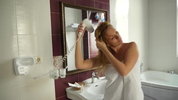 Kadın kuru ıslak saçlar yavaş hareket. Bir kadın banyoda bir saç kurutma makinesi kullanır. 4k — Stok video