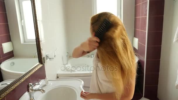 Медленное движение женских влажных волос. Женщина пользуется феном в ванной комнате. 4k — стоковое видео