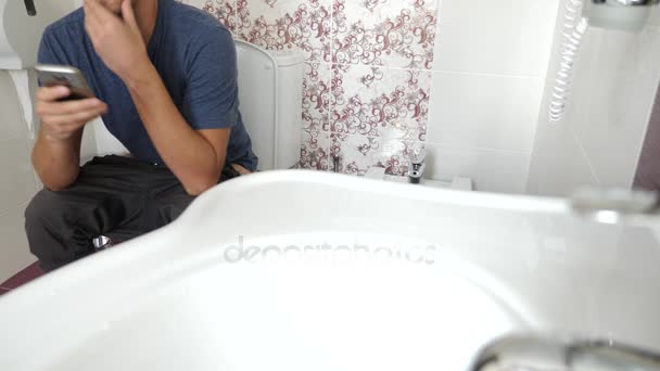 남자는 화장실에 앉아서 휴대 전화에서. 4 k, 슬로우 모션 — 비디오
