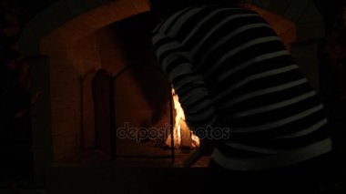 Bir şömine ateş. 4k, ağır çekim. kadın yakacak odun şöminede koyar.