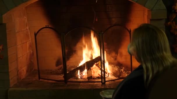 Fuego en una chimenea, 4k, cámara lenta. mujer beber té cerca de la chimenea — Vídeo de stock