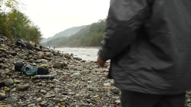 4k. the guy puts a tourist tent on the shore of a mountain river. — Stock Video