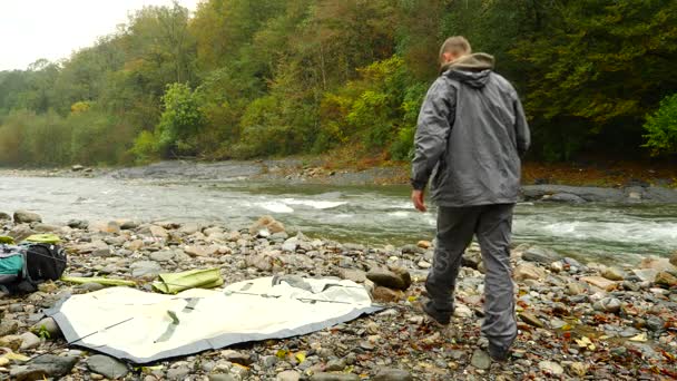 4 k. ο τύπος βάζει μια τουριστική σκηνή στην όχθη ενός ποταμού στο βουνό. — Αρχείο Βίντεο