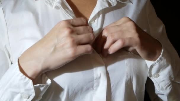 Yakın çekim, ayrıntılar. bir kadın onun beyaz gömlek üzerinde üst düğmesini unfastens, onu kaldırır. — Stok video