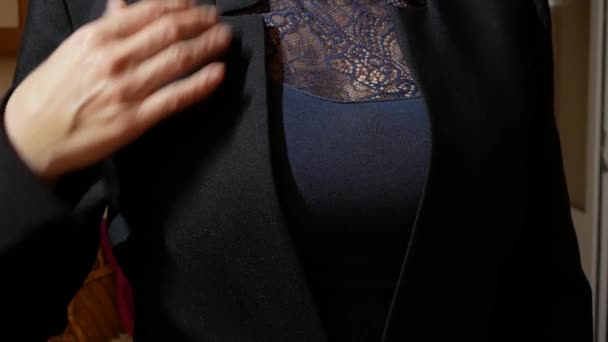Uma mulher com um belo peito coloca uma jaqueta preta — Vídeo de Stock
