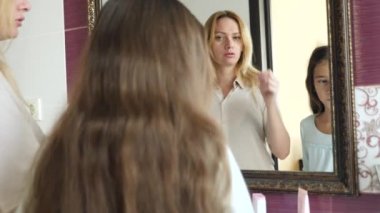 Anne ve kızı evde aynada diş fırçalama. 4k, ağır çekim