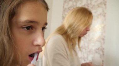 Anne ve kızı evde aynada diş fırçalama. 4k, ağır çekim