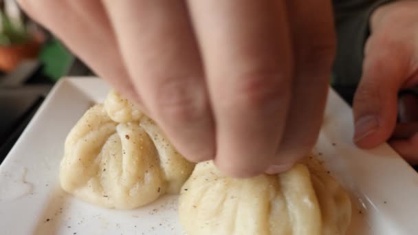 Heißes georgisches Chinkali auf einem Teller. Jemand isst Chinkali-Hände. 4k. Zeitlupe — Stockvideo