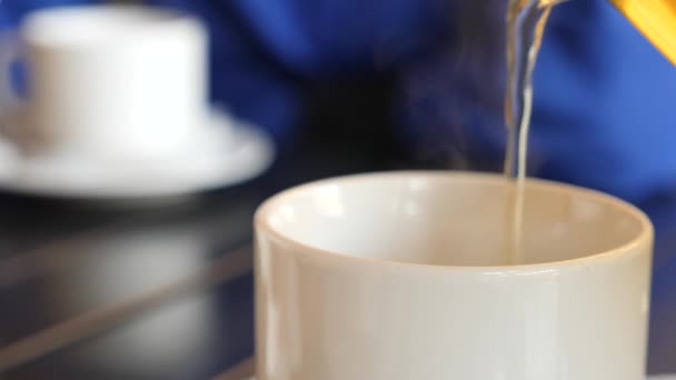 4k, αργή mosomeone χύνει το τσάι από μια τσαγιέρα από πορσελάνη λευκό σε μια κούπα λευκό. 4k, αργή motiontion. — Αρχείο Βίντεο