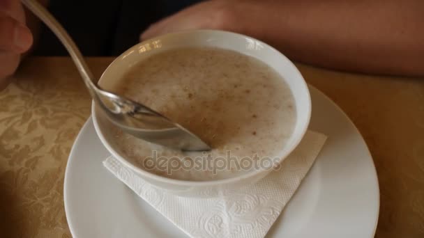 Someone is eating hot oatmeal for breakfast in a cold cafe. 4k, slow motion — Stock Video