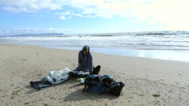 Denizin kenarında plajda kamp çadır. 4k, ağır çekim. bir adam bir çadır rüzgarlı havalarda kumlu bir plaj üzerinde kurar