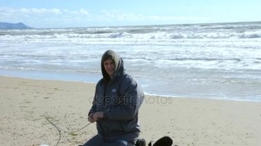 Denizin kenarında plajda kamp çadır. 4k, ağır çekim. bir adam bir çadır rüzgarlı havalarda kumlu bir plaj üzerinde kurar