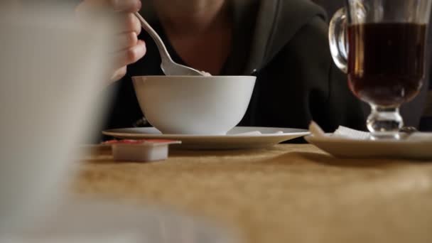 Iemand is het eten van warme havermout voor het ontbijt in een koude café. 4k, slow-motion — Stockvideo