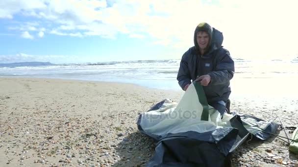 Camping tente sur la plage au bord de la mer. 4k, au ralenti. un homme dresse une tente par temps venteux sur une plage de sable — Video