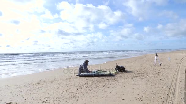 Kemping sátor a tengerparton, a tengerparton. 4k, lassú mozgás. egy ember beállítja egy sátorban szeles időjárás, a homokos tengerparton — Stock videók