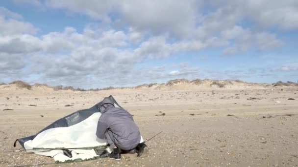 Kemping sátor a tengerparton, a tengerparton. 4k, lassú mozgás. egy ember beállítja egy sátorban szeles időjárás, a homokos tengerparton — Stock videók