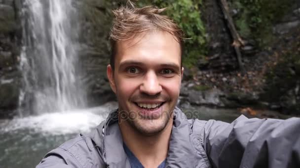快乐的男子背包客享受惊人的热带瀑布。旅行生活方式和成功概念假期入狂放的自然在背景山。4k、慢动作 — 图库视频影像