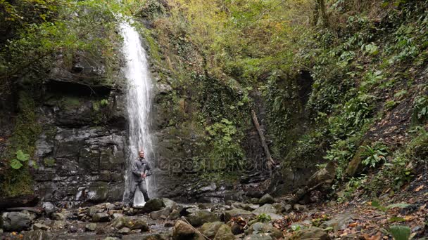 Счастливый человек-рюкзак, наслаждающийся удивительным водопадом. 4k, slow motion — стоковое видео