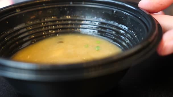 Ein Mann isst in einem Schnellrestaurant chinesisches Essen. 4k. Zeitlupe. Er isst Suppe aus einem Einwegteller — Stockvideo