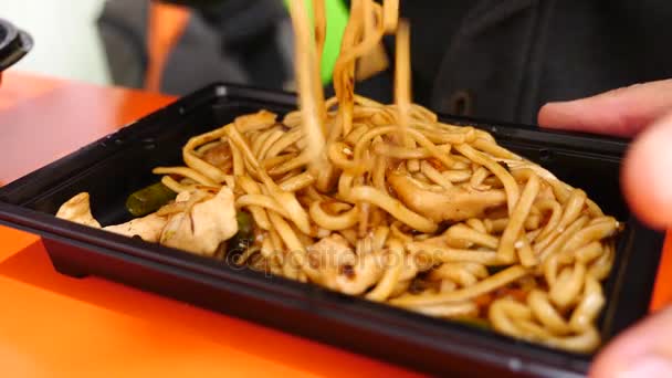 El hombre está comiendo fideos chinos con palillos. 4k. Disparo lento . — Vídeo de stock