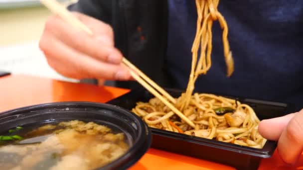 Quell'uomo sta mangiando spaghetti cinesi con le bacchette. 4k. Tiro lento . — Video Stock