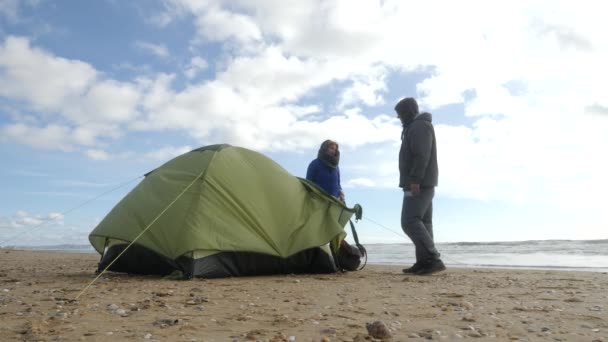 Denizin kenarında plajda kamp çadır. 4k, ağır çekim. erkek ve kadın sahilde çadır kurmak. — Stok video