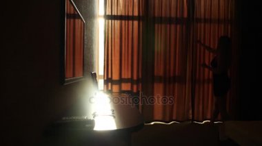 Mutlu çifte sarılma ve öpüşme panoramik yatak odası penceresinin önünde. Pencereden gelen güneş ışığı. 4 k. ağır çekim