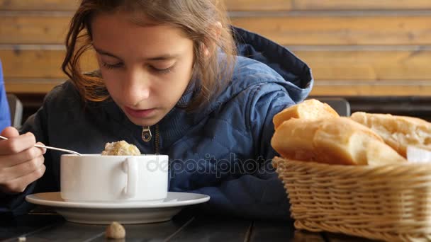 女の子は、屋外のカフェでホット チキン ヌードル スープを食べています。4 k、スローモーション。クローズ アップ — ストック動画