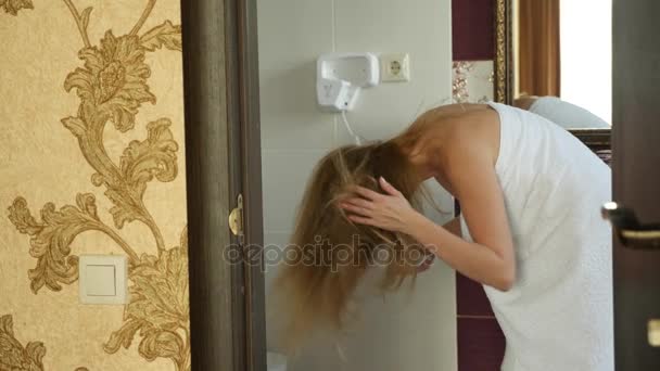 Медленное движение женских влажных волос. Женщина пользуется феном в ванной комнате. 4k — стоковое видео