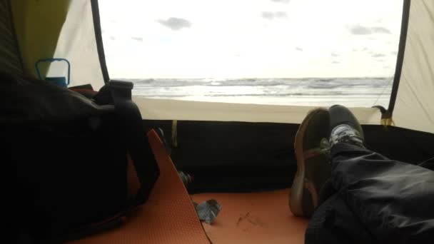 Ноги на заднем плане из палатки на море. Кемпинг палатка на пляже у моря. 4k, slow motion . — стоковое видео