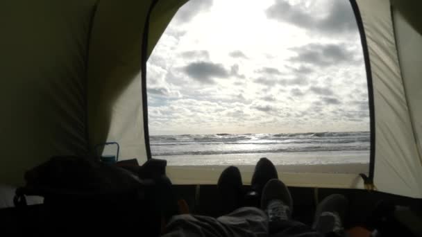 Pés no fundo de uma vista de uma tenda no mar. Tenda de acampamento na praia junto ao mar. 4k, câmera lenta . — Vídeo de Stock
