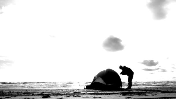 海のビーチでキャンプのテント。4 k、スローモーション。ビーチにテントを立てた男. — ストック動画