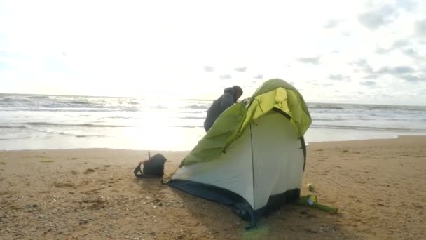 Tenda de acampamento na praia junto ao mar. 4K, câmara lenta. homem montou uma tenda na praia . — Vídeo de Stock