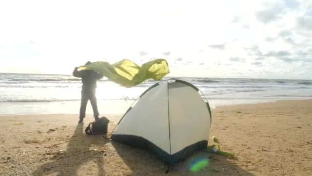 바다로 해변에 캠핑 텐트입니다. 4 케이, 슬로우 모션입니다. 해변에 텐트를 설정 하는 남자. — 비디오