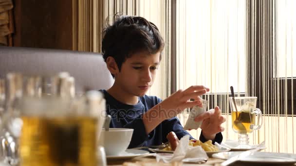 Мальчик завтракает в кафе. 4k, slow motion — стоковое видео