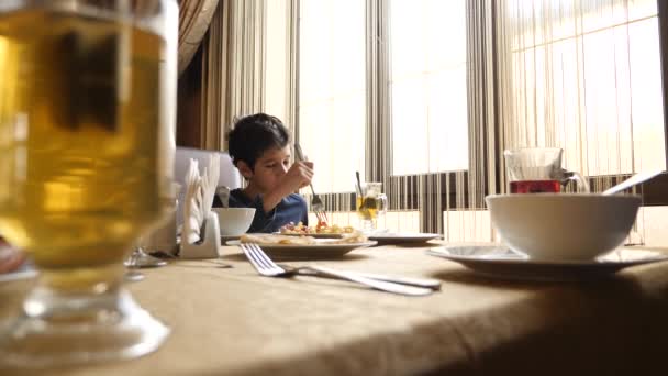 Fiú reggeli elfogyasztására a kávézóban. 4k, lassú mozgás — Stock videók