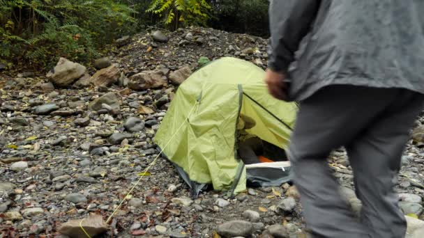 4k. a guy and a girl near a tourist tent on the bank of a mountain river. — Stock Video