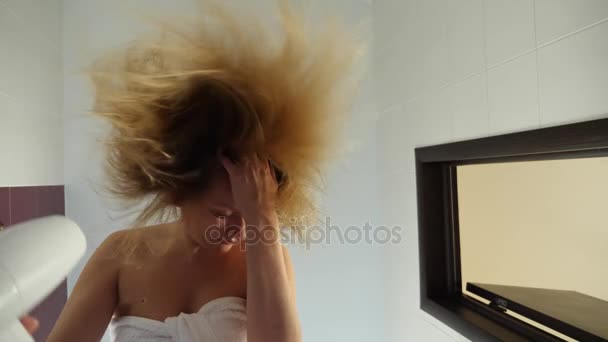 Mouvement lent des cheveux secs humides femelles. Une femme utilise un sèche-cheveux dans la salle de bain. 4k — Video