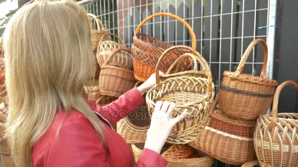 Una mujer elige una canasta de mimbre en una feria de artesanía popular. 4k, cámara lenta — Vídeos de Stock