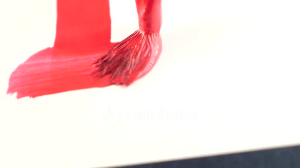 Någon drar färg på ett vitt ark. närbild av en tofs. 4k, slowmotion. ritar ett kors med röd färg på ett vitt ark — Stockvideo