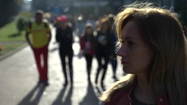 Woman standing against the background of an anonymous crowd of people walking down the street. 4k slow motion — Stock Video