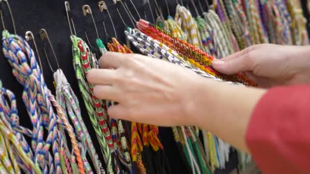 Belle décoration hippie. la femme regarde à travers les ornements dans la vitrine du marché de rue. 4k, au ralenti — Video