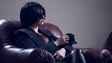 Sıcak esmer güneş gözlüğü yuvarlak, bir koltukta oturur ve siyah bir kedi okşadı. 4k, ağır çekim