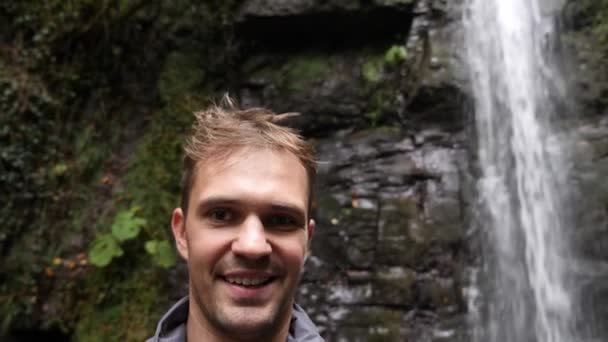 Hombre feliz mochilero disfrutando de increíbles cataratas tropicales.Viajes Estilo de vida y el éxito concepto de vacaciones en la naturaleza salvaje en la montaña de fondo. 4k, cámara lenta — Vídeo de stock